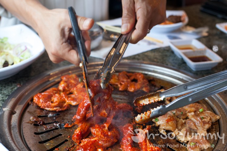 cutting meat over the grill at Taegukgi Korean BBQ cutting meat over the grill at Taegukgi Korean BBQ